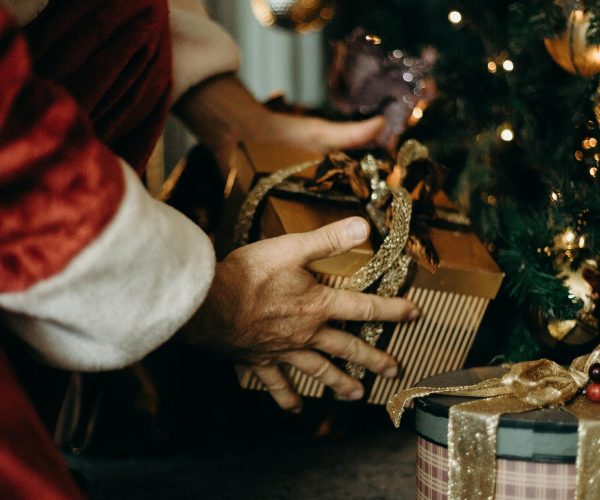 Santa Claus placing gifts under a beautifully decorated Christmas tree, capturing the holiday spirit.