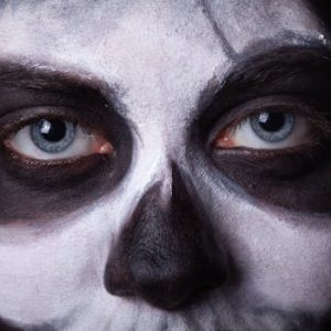 Intense close-up of a face painted with spooky Halloween skull makeup, featuring haunting eyes.