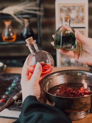 Hands mix colorful potions in a wizarding world themed setup with spellbook and wand.